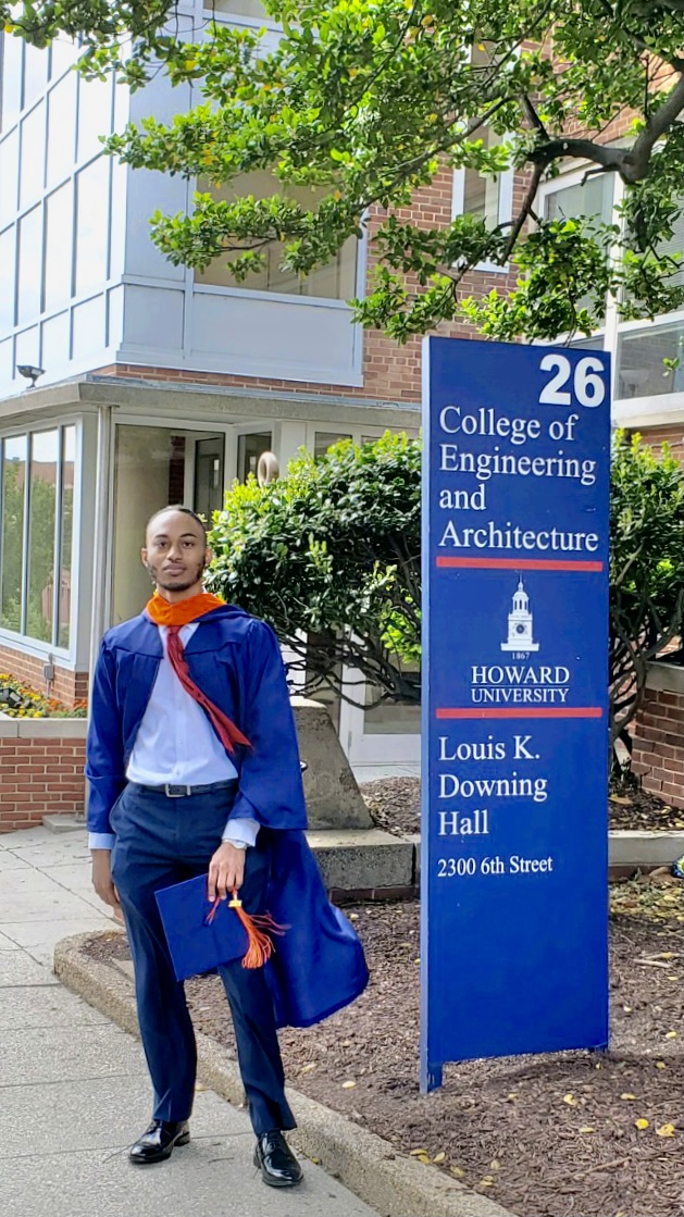 Me, standing next to the Howard University College of Engineering and Architecture Lewis K. Downing Building. I'm wearing an open graduation gown revealing a formal outfit.
